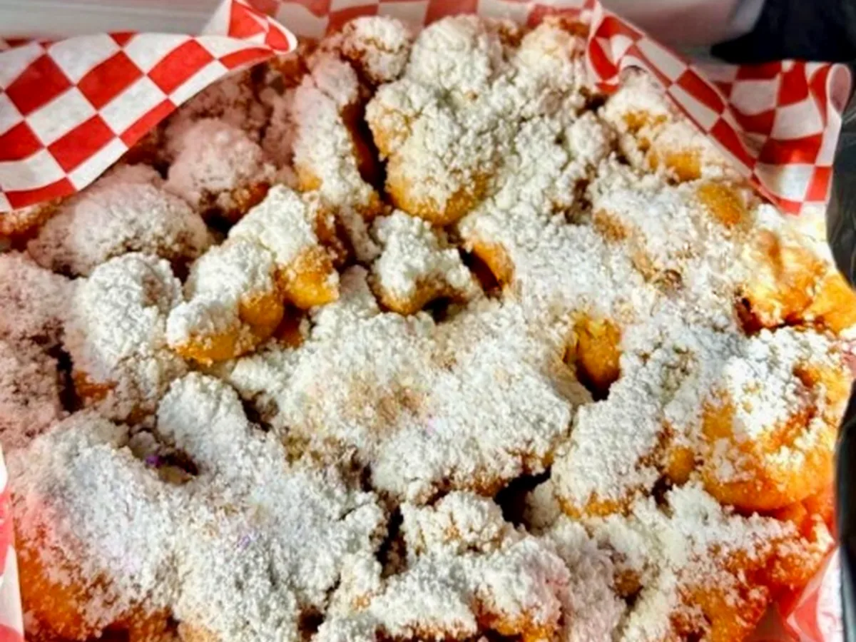 Deep-fried treats dusted with powdered sugar in a checkered basket