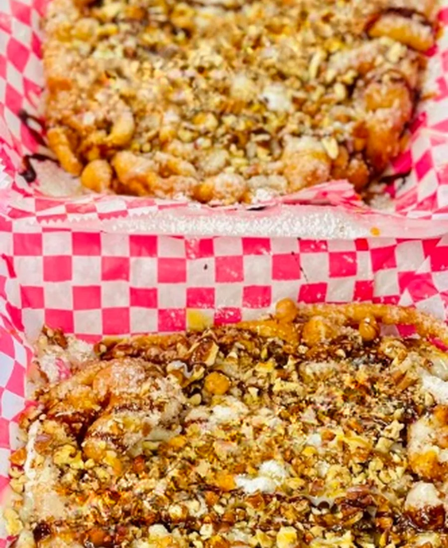 Classic funnel cake dusted with powdered sugar in a checkered basket
